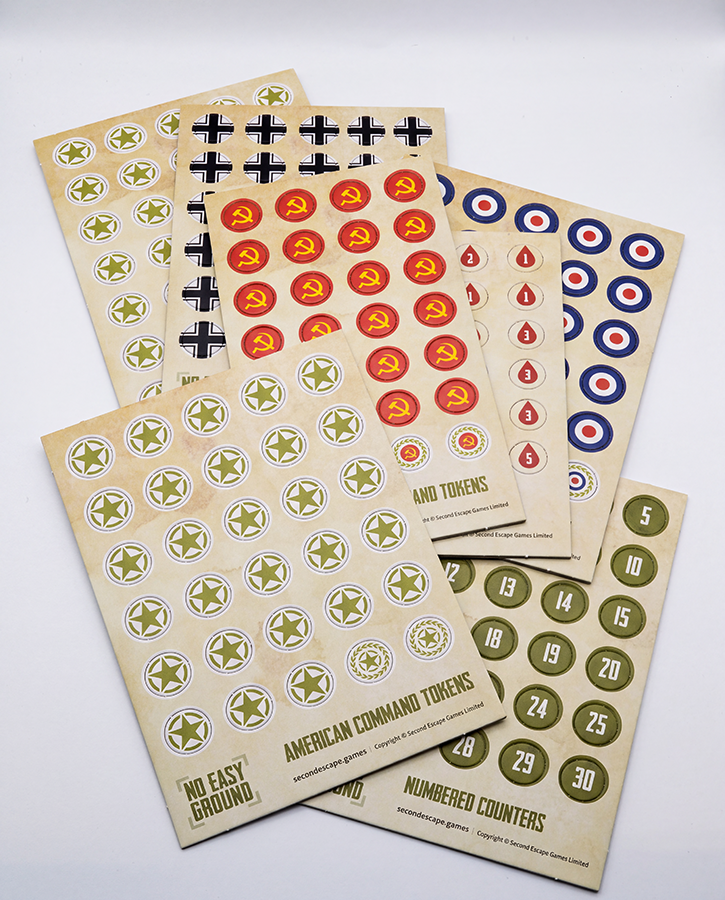 Two printed sticker sheets for a board game, one with black and gray German cross tokens and the other with red circular Soviet command tokens featuring yellow hammer and sickle symbols, on a light gray background.
